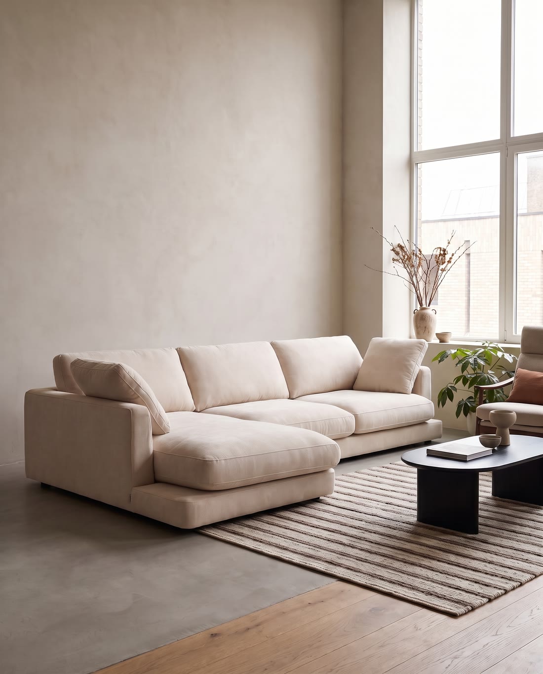 A pale modular sofa on a striped rug in a bright room with a low black table.